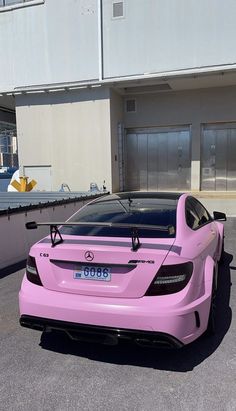 a pink sports car parked in front of a building