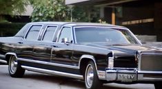 an old black station wagon parked in front of a building