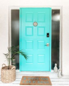 a blue front door with two planters and a rug on the floor next to it