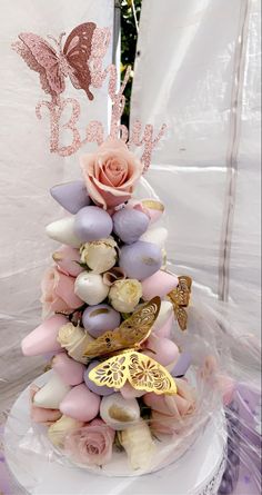 a cake decorated with flowers and butterflies on top of a white tablecloth covered table