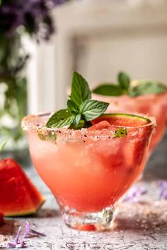 watermelon margaritas with mint garnish on the rim and purple flowers