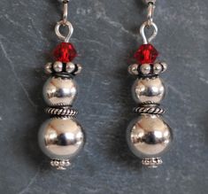 These Holiday earrings are made with 8mm and 6mm round silver beads. silver spacer beads and a glass bead for a hat. Fun and festive all season long. Choose from A. a more cone shaped red hat top or B. a more flat red hat top. Silver ear wires. About 1" long. Holiday Beaded Jewelry, Bead Snowman, Christmas Jewelry Diy, Snowman Earrings, Wire Wrap Jewelry Designs, Holiday Beading, Beadwork Necklace, Wire Beads, Holiday Earrings