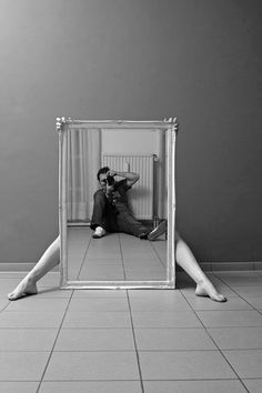 a man and woman sitting on the floor in front of a mirror with their legs crossed