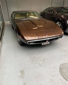 two cars parked in a garage next to each other on the floor and one is brown