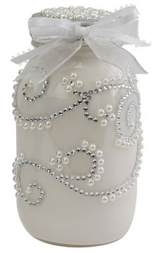 a white glass jar with pearls and a bow on the top is decorated with beads