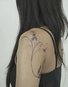 the back of a woman's shoulder with flowers and leaves on her left arm