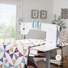 a sewing machine sitting on top of a wooden table next to a quilted blanket