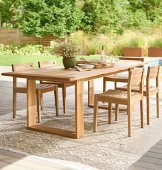 a wooden table with four chairs and a potted plant sitting on top of it