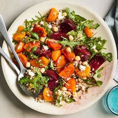 a white plate topped with beets, carrots and feta cheese next to a glass of water