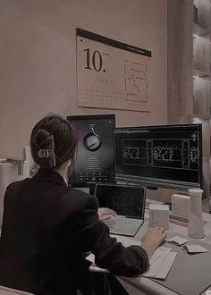 a woman sitting at a desk in front of two computer monitors with headphones on