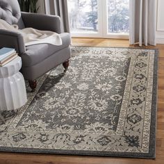 a living room area with a chair and rug on the hardwood floor, next to a large window