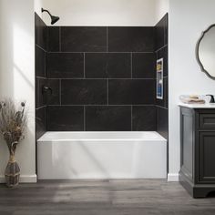 a black and white bathroom with a tub, sink, mirror and toilet paper dispenser