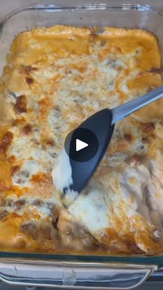 a casserole dish with meat and cheese being stirred with a spatula in it