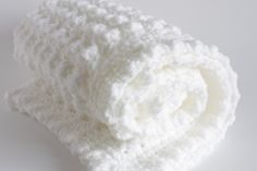 a white crocheted blanket laying on top of a table