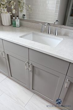 a bathroom sink sitting under a mirror next to a white counter top with two faucets