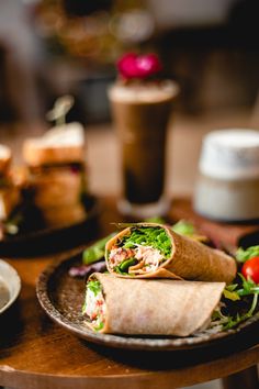 there is a wrap on the plate with lettuce and tomatoes in front of it