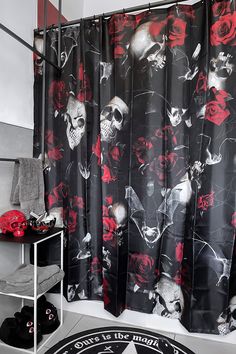 a black and red shower curtain with skulls and roses on it is next to a chair