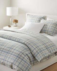 the bed is made with plaid sheets and pillows