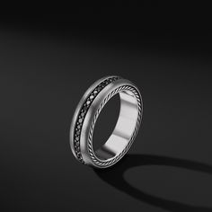 a white gold ring with black diamonds in the center on a dark background, close up