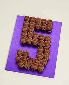 the letter e is made out of cupcakes on a purple paper with scissors