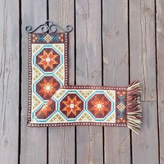 a decorative wall hanging on the side of a wooden fence with a metal hook and tassel