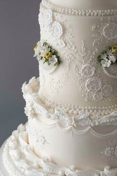 a wedding cake with white frosting and flowers on it's side, sitting on a plate