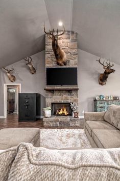 a living room with deer heads mounted on the wall and a fireplace in the center