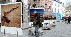 there is a man walking down the street in front of some posters on the sidewalk