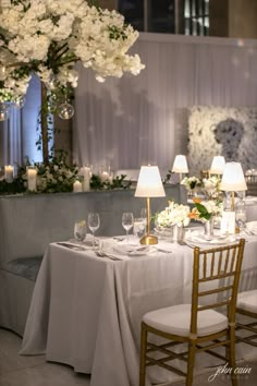 the table is set with white flowers, candles and place settings for two people to sit at