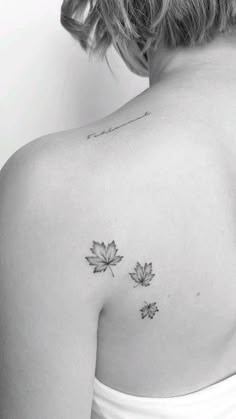 the back of a woman's shoulder with two maple leaves on her left arm