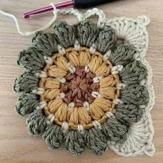 a crocheted doily on a wooden table with a knitting needle next to it