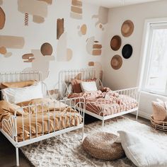 two twin beds in a bedroom with wallpaper and pillows on the walls, next to each other