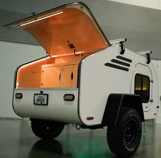 an off - road camper is parked in a building with its doors open and the hood up