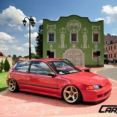 a red car parked in front of a green building