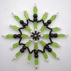 a green and black beaded snowflake with white pearls on it's sides