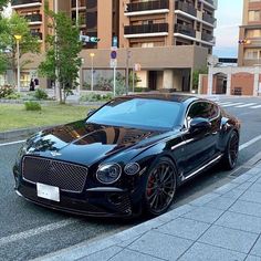 a black car is parked on the side of the road in front of some buildings