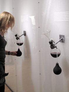 a woman standing next to a wall with wine glasses hanging from it's hooks