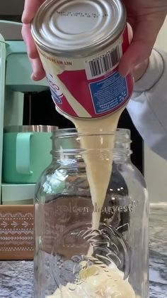 a person pours cream into a glass jar