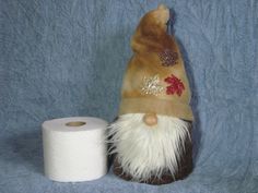 a brown and white gnome hat next to a roll of toilet paper on a blue background