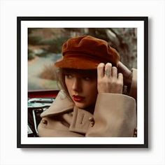 a woman wearing a brown hat is holding her hand up to her head while sitting in a car