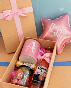 an open box filled with condiments and drinks next to a pink foil balloon