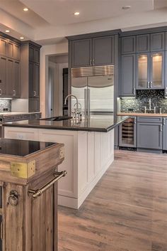 a large kitchen with an island in the middle and stainless steel appliances on both sides