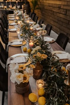 a long table is set with candles and flowers on it, along with other place settings