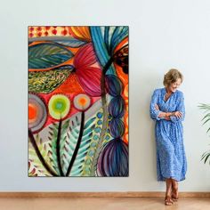 a woman standing in front of a painting on the wall next to a plant and potted plant