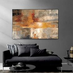 an abstract painting hangs on the wall above a black couch in a modern living room