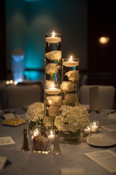 candles and flowers are arranged on the table for an elegant centerpiece at this wedding reception