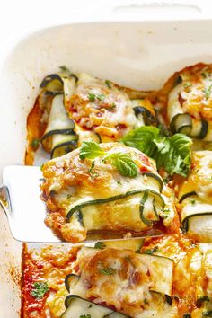 zucchini and cheese casserole in a white dish with a serving spoon