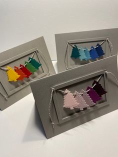 three cards with different colors of paper cut out of the shape of trees on them