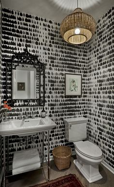 a white toilet sitting next to a sink in a bathroom under a round light fixture