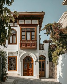 a large white house with wooden doors and windows on the side of it's building